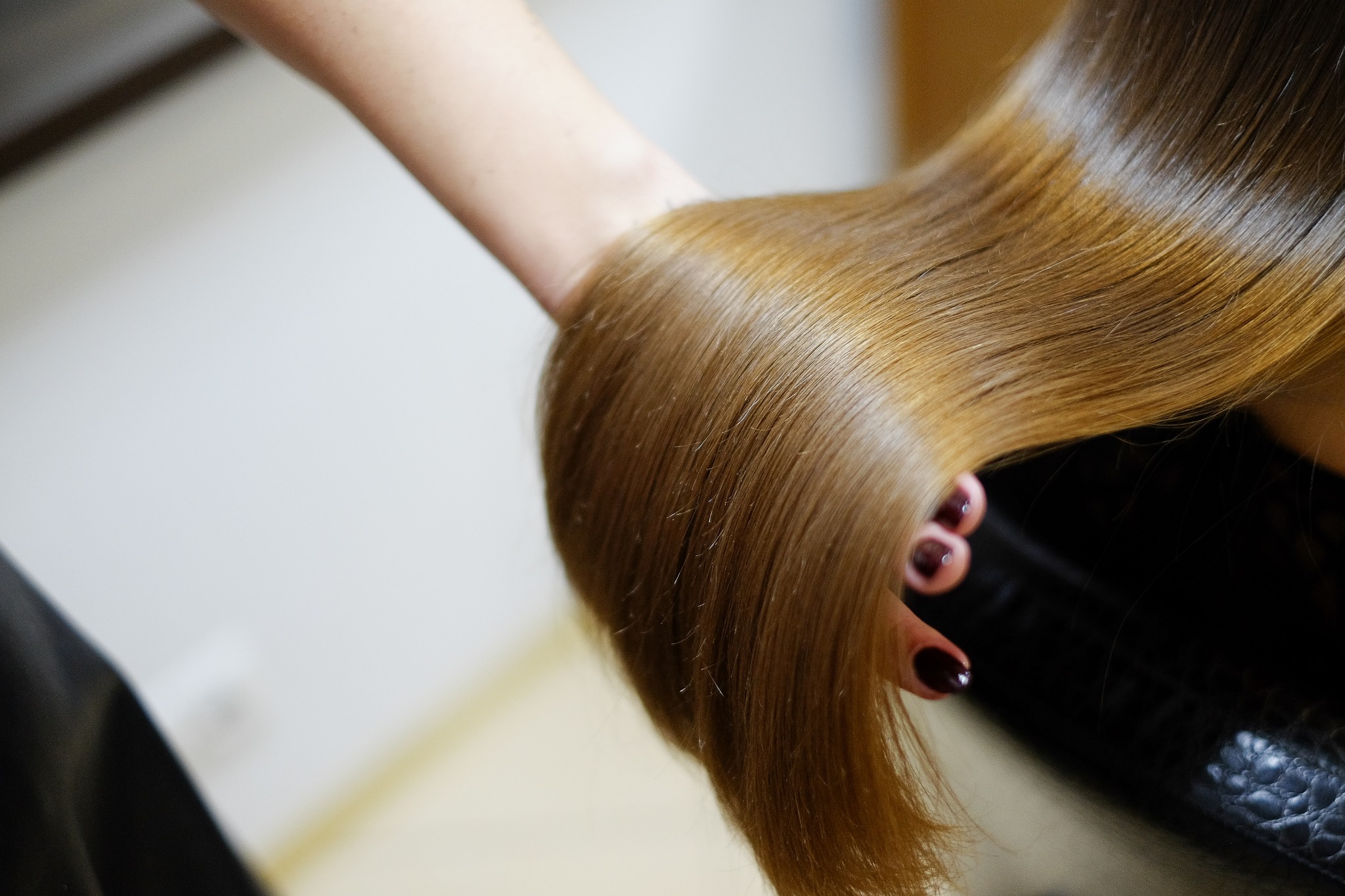 A stylist holding out someone's long hair showing how it has the glass hair style